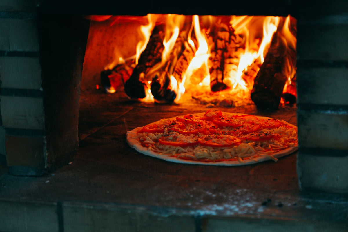 Zelfgemaakte pizza gebakken in een houtgestookte pizza-oven met vlammen